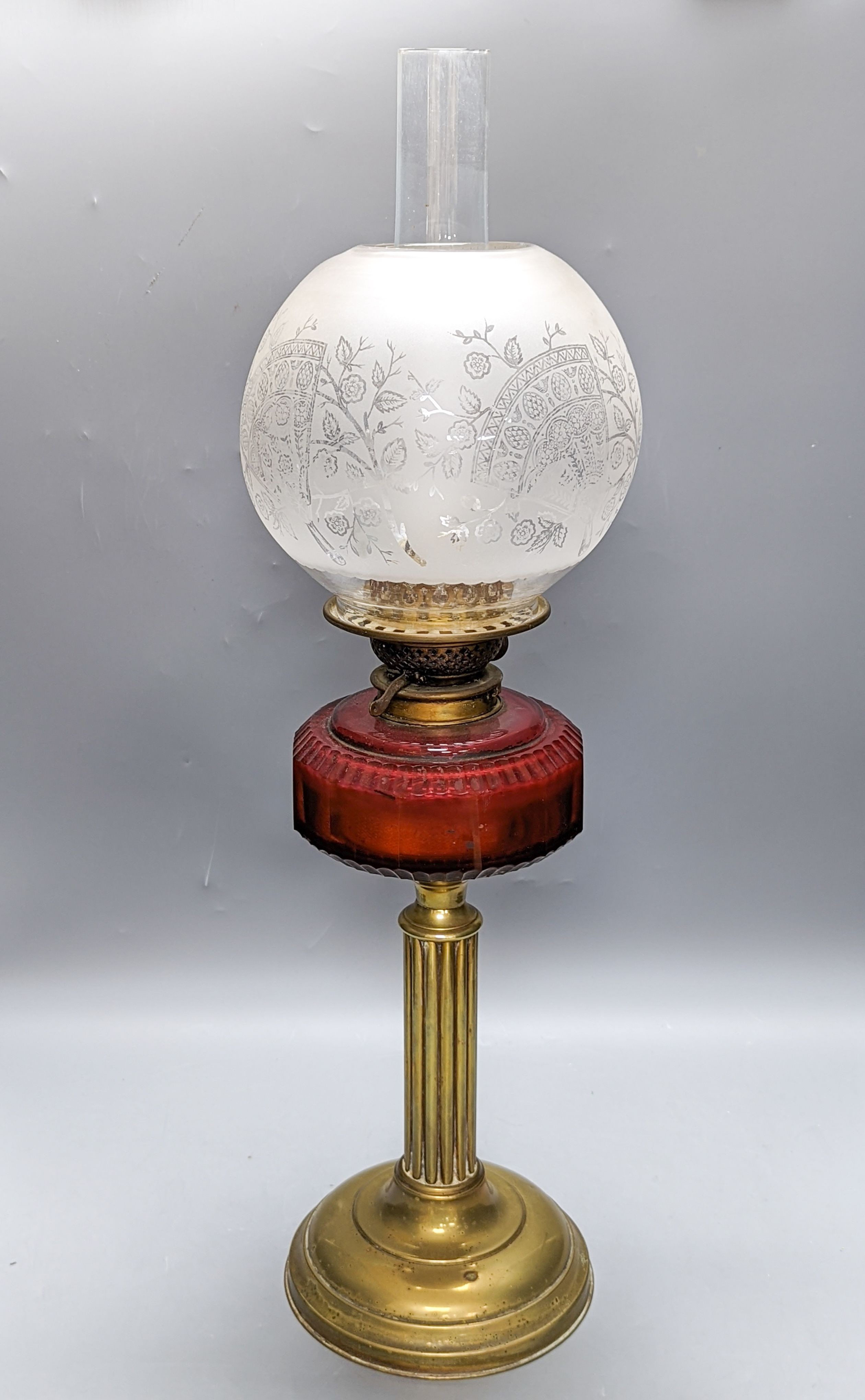 A Victorian brass oil lamp with etched glass shade and cranberry reservoir. 64cm total height